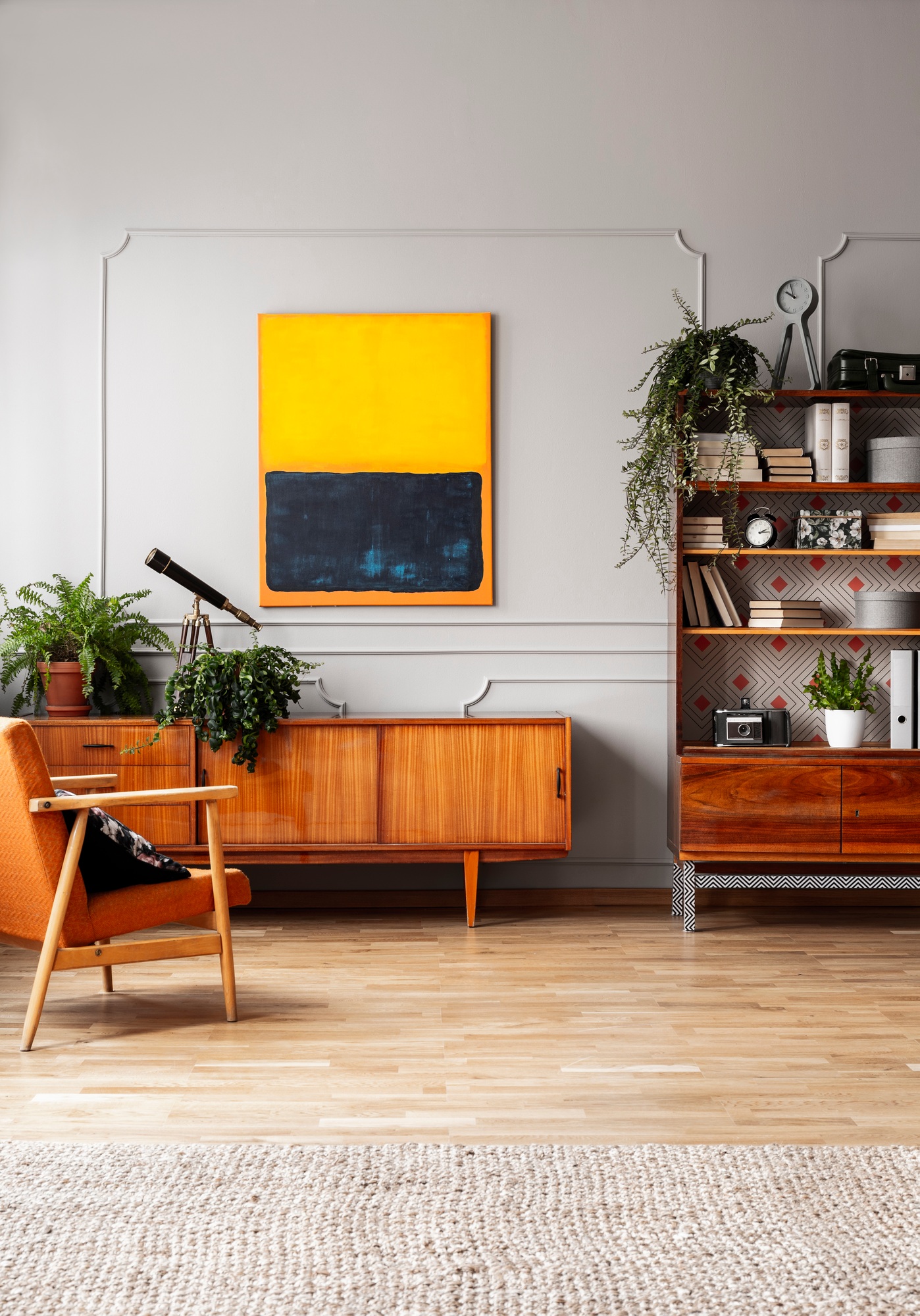 Orange painting above wooden cupboard in retro flat interior wit